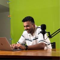 Raksham Shahu, founder of Fitastic Digital Media, at his desk with a laptop and microphone